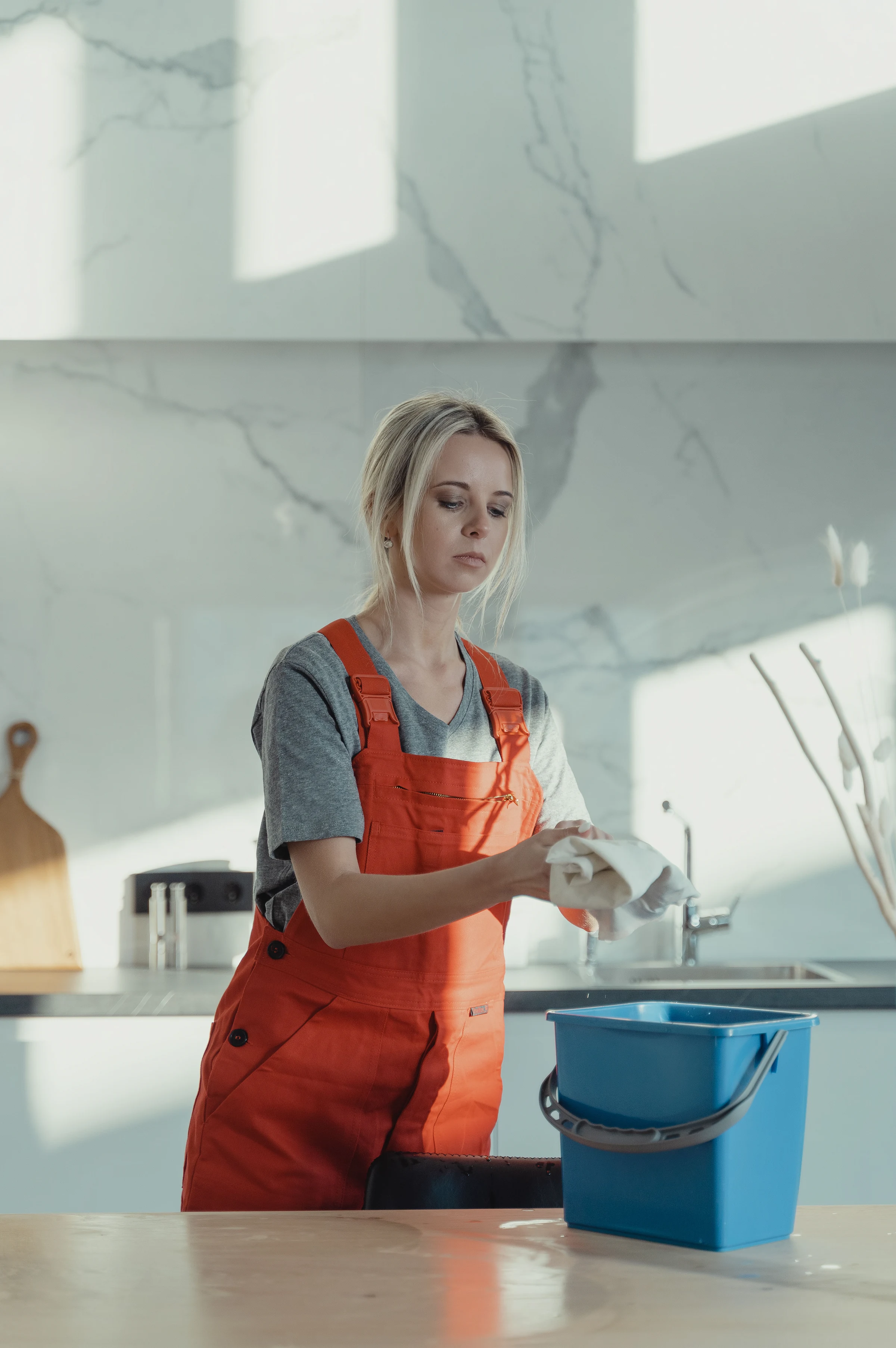 A cleaner in overalls wiping a kitchen counter