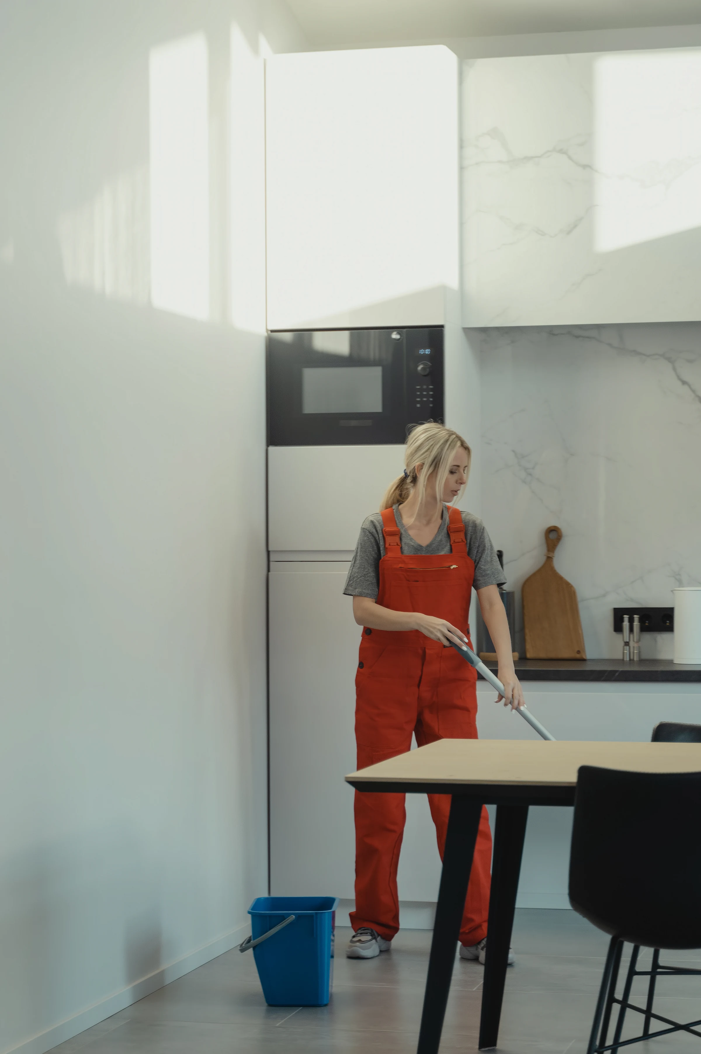 A cleaner mopping the floor of a bright kitchen